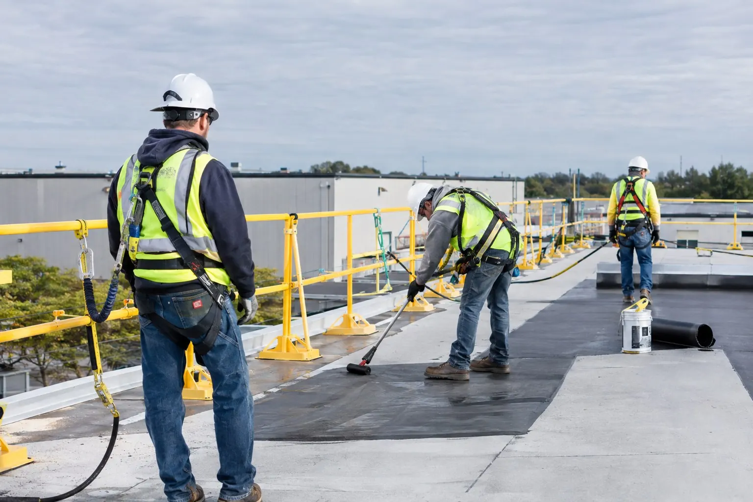Commercial roofing crew working behind guardrails on a flat roof
