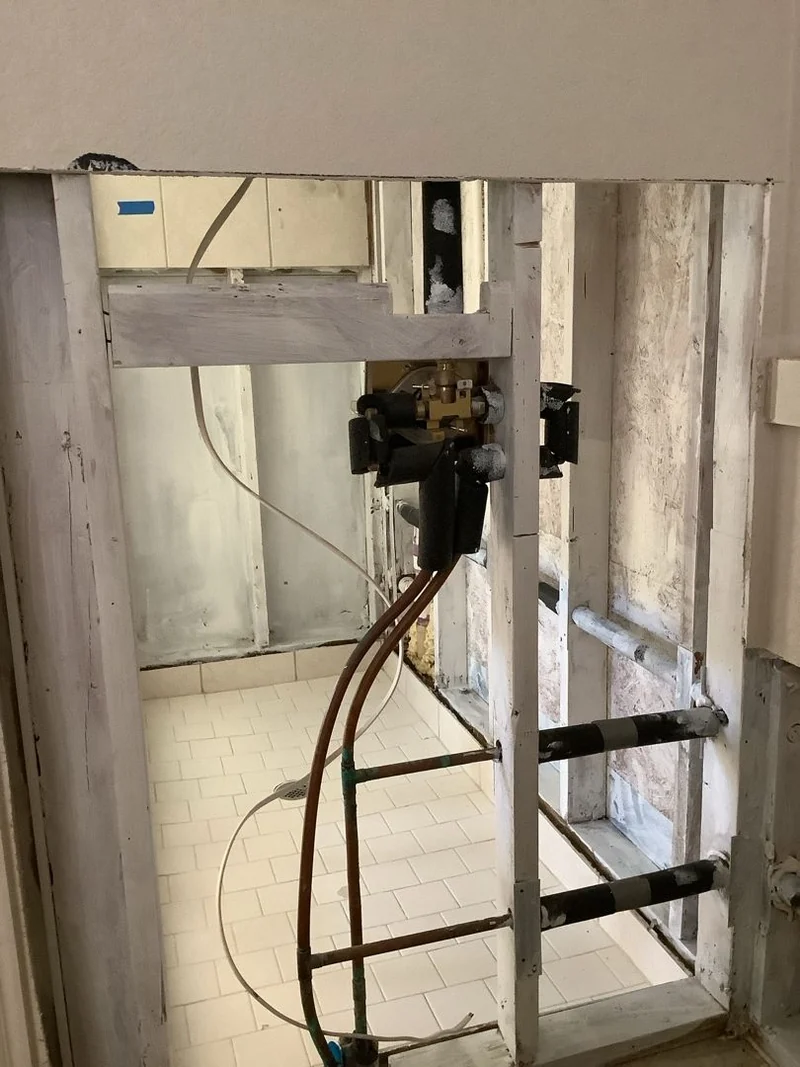 Opened wall and plumbing area in the Southlake project final-walkthrough photos